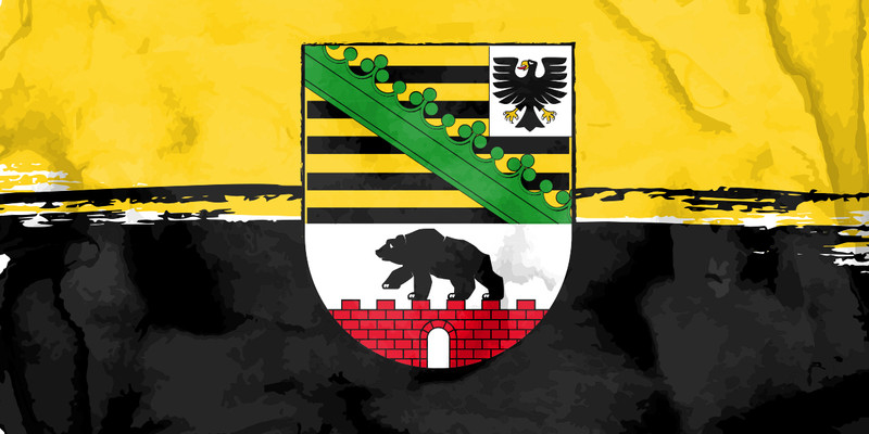 KI generiert: Das Bild zeigt die Flagge von Sachsen-Anhalt mit dem Landeswappen in der Mitte. Das Wappen enthält schwarze und gelbe Streifen, einen grünen Rautenzweig und einen Bären auf einer roten Mauer.