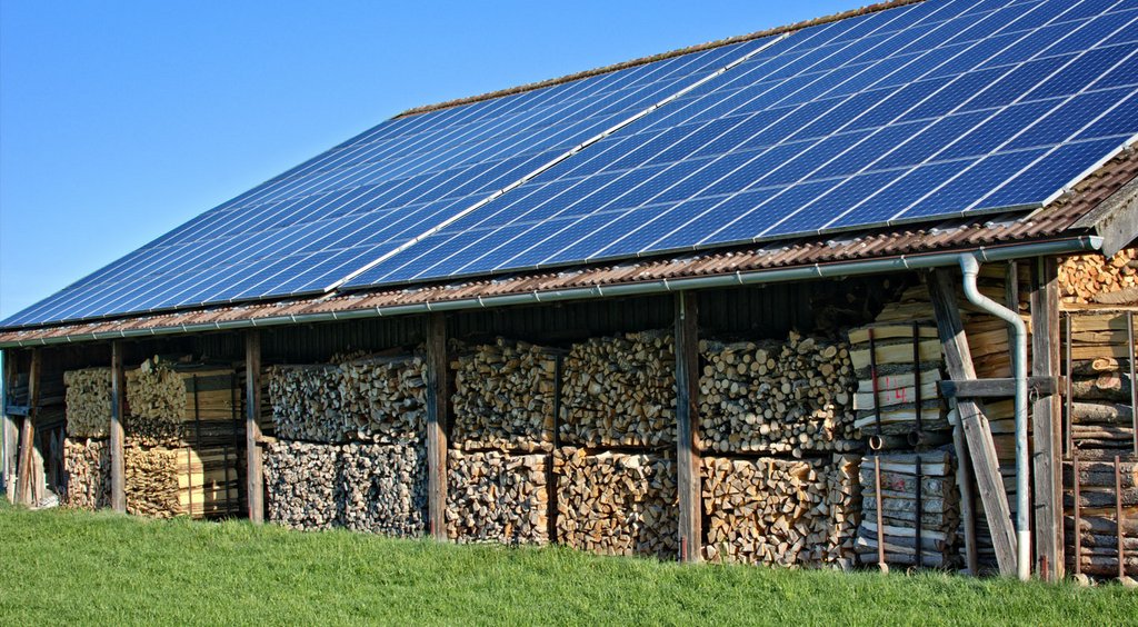 Auf einem Dach eines Gebäudes, das zur Lagerung von Holz genutzt wird, befindet sich eine Photovoltaikanlage.