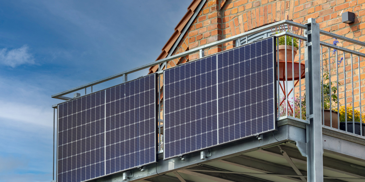KI generiert: Auf dem Bild sind zwei Solarpaneele zu sehen, die an einem Balkongeländer eines Backsteinhauses montiert sind. Der Hauptinhalt fokussiert sich auf die Nutzung von Solartechnologie in Wohngebieten.