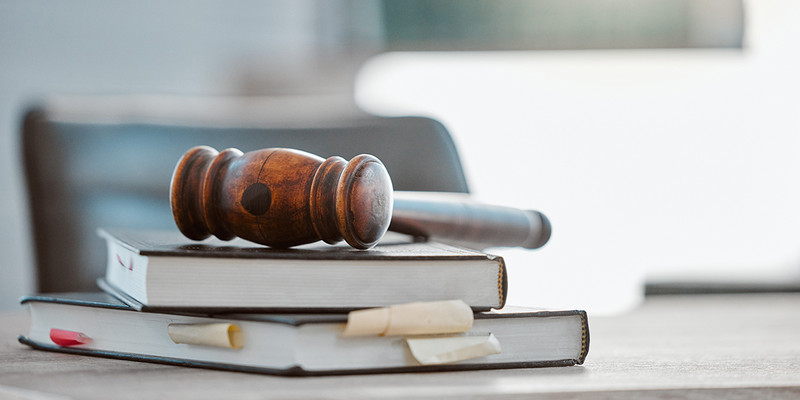 KI generiert: Das Bild zeigt einen Holzrichterhammer, der auf einem Stapel Bücher liegt. Der Hauptinhalt des Bildes vermittelt ein juristisches oder rechtliches Thema.