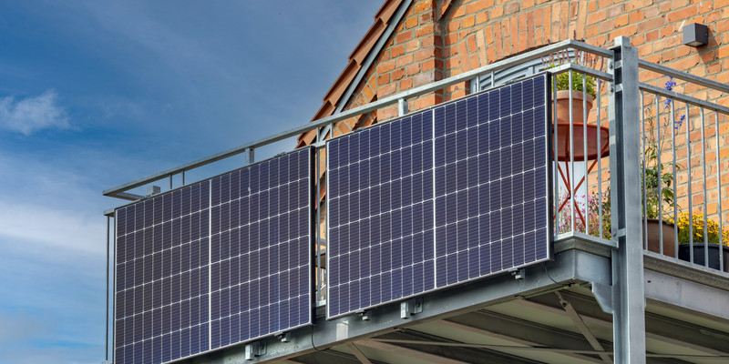KI generiert: Auf dem Bild sind zwei Solarpaneele zu sehen, die an einem Balkongeländer eines Backsteinhauses montiert sind. Der Hauptinhalt fokussiert sich auf die Nutzung von Solartechnologie in Wohngebieten.